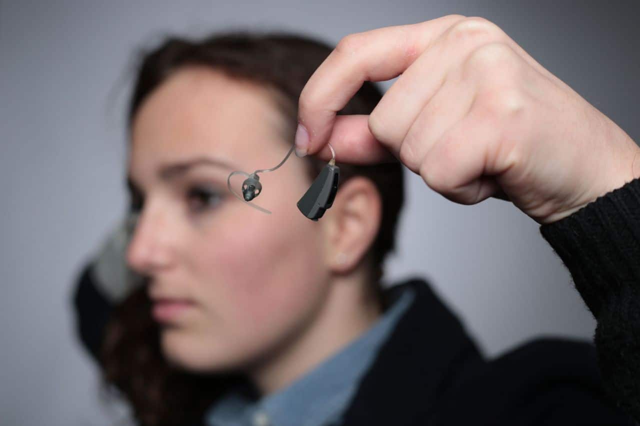 Une prothèse auditive tenue en main
